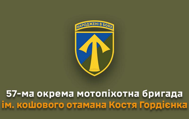 Зображення військового шеврона 57 ОМПБр. На щиті синьо-зеленого кольору зображено золотий наконечник стріли (спис). Угорі на жовтій стрічці напис 'НАРОДЖЕНІ В БОЯХ'. Під шевроном текст: '57-ма окрема мотопіхотна бригада ім. кошового отамана Костя Гордієнка'.