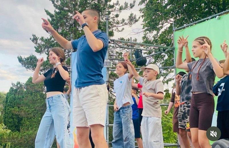 Аніматори та діти танцюють під час активного відпочинку на літній сцені табору