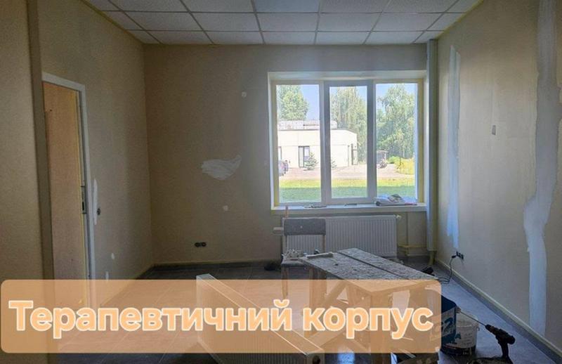 Кімната в терапевтичному корпусі на стадії оздоблення: ошпакльовані стіни, встановлене велике металопластикове вікно, радіатор опалення та будівельні риштовання.