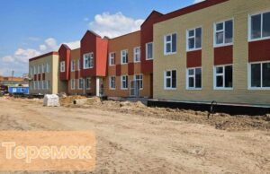Загальний вид новозбудованої будівлі дитячого садка «Теремок» із сучасною обшивкою фасаду в бежевих, червоних та коричневих тонах. На подвір'ї тривають роботи з благоустрою.