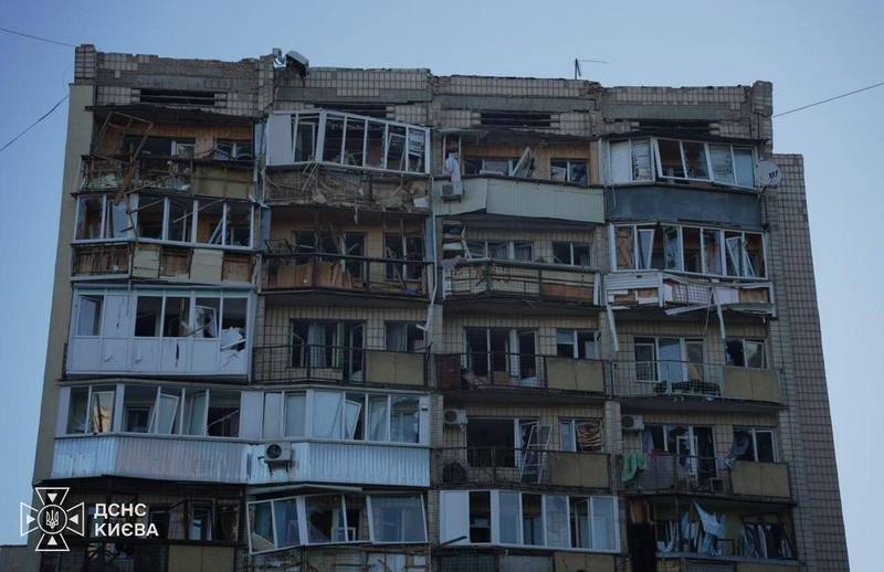 Фасад багатоповерхівки із вибитими шибками, пошкодженими балконами та рамами внаслідок вибухової хвилі від російської атаки.