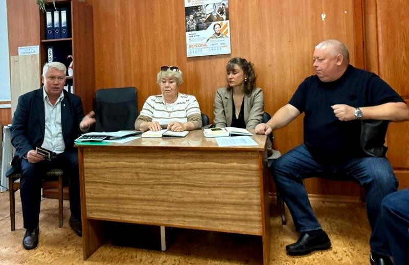 Робоча нарада в Макарівській громаді. За столом сидять керівники та фахівці, обговорюючи питання супроводу ветеранів та їхніх родин. На стіні висить інформаційний плакат.