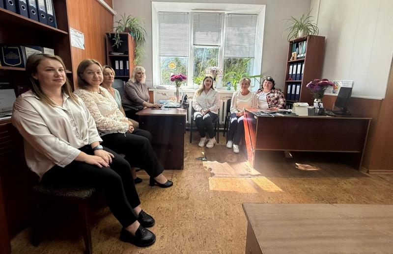 Інтер'єр робочого кабінету, де сидять кілька жінок (фахівчині із супроводу ветеранів). Кімната освітлена природним світлом, на столах документи та квіти.