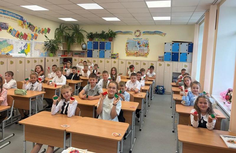 Учні початкового класу Макарівського ліцею №2 сидять за партами в оновленому кабінеті, посміхаються та тримають у руках кольорові деталі конструктора LEGO