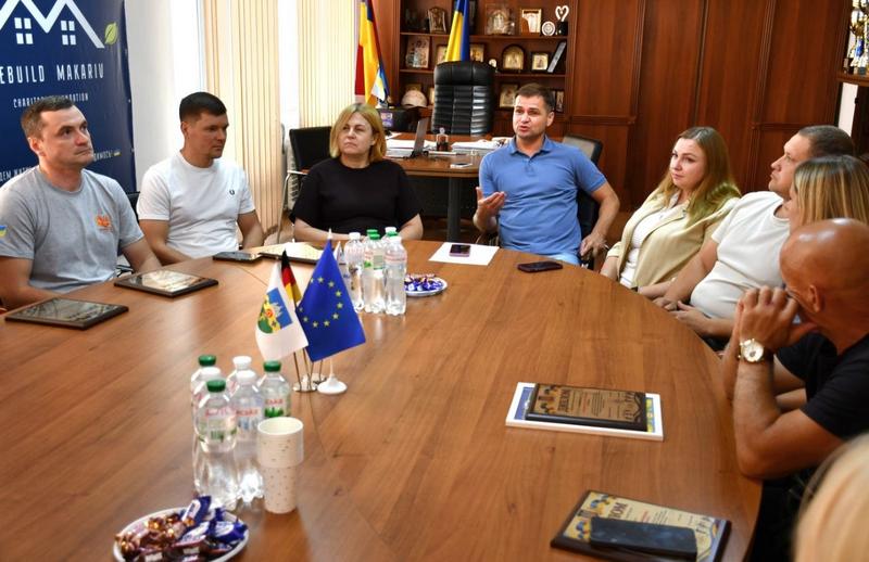 Виступ директора ФСК «Макарівська громада» Олександра Богдюка перед представниками спортивної сфери під час урочистого нагородження. На передньому плані видно нагороди та прапори України і ЄС.